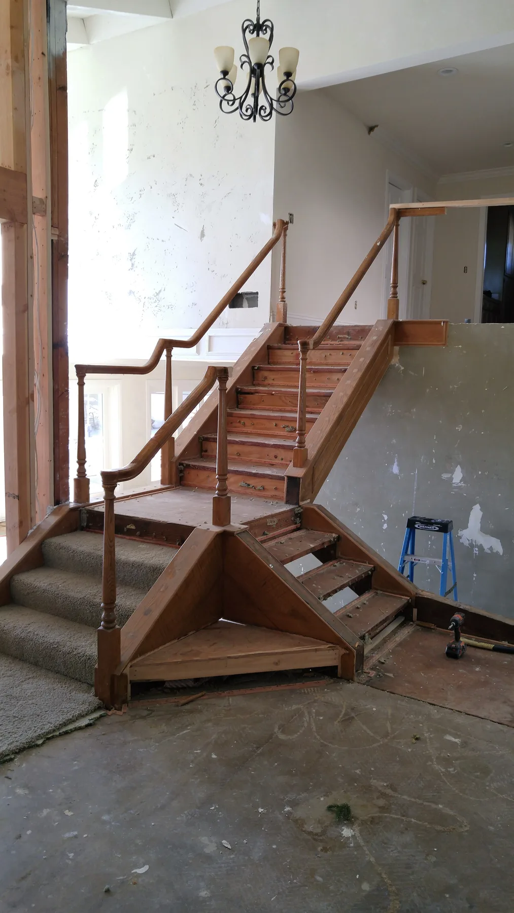 Original stair opening before rebuild: Corona custom stair rebuild project by PL Builders with wood posts and metal railing