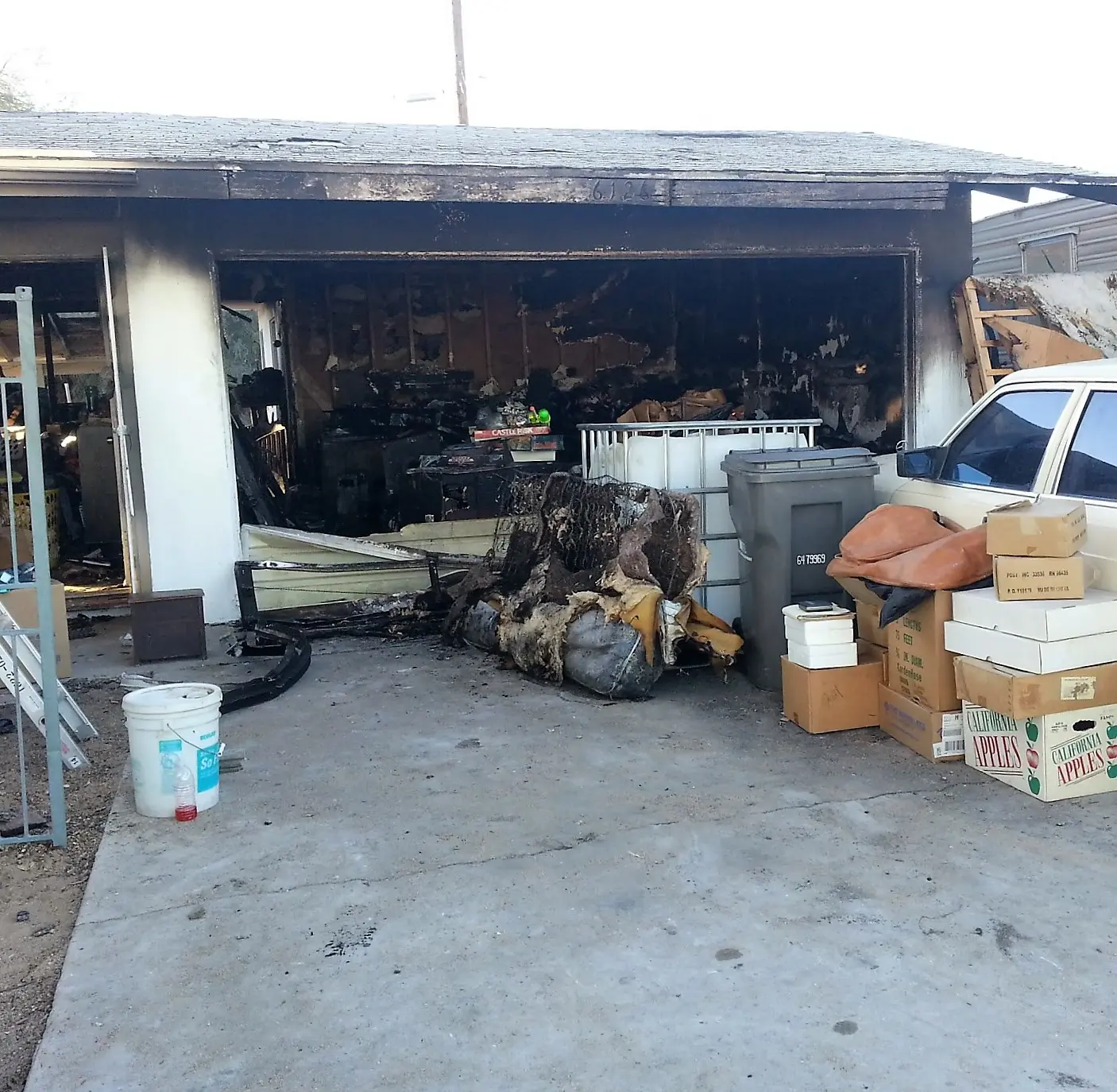 Twentynine Palms garage fire emergency board up and roof tarp project by PL Builders showing fire damaged garage contents before emergency board up
